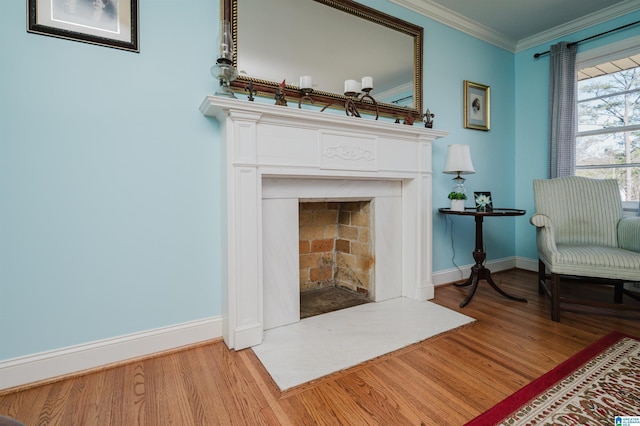 sitting room with baseboards, a fireplace with flush hearth, wood finished floors, and crown molding