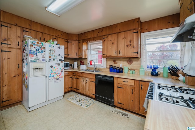 kitchen with black dishwasher, light floors, white fridge with ice dispenser, and a sink