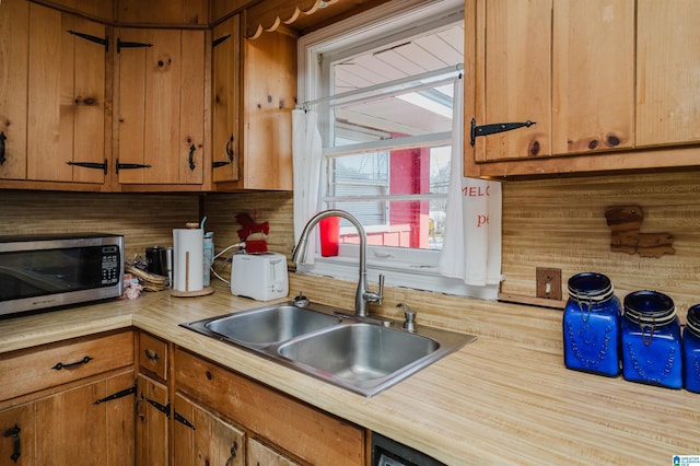 kitchen with stainless steel microwave, light countertops, brown cabinets, and a sink