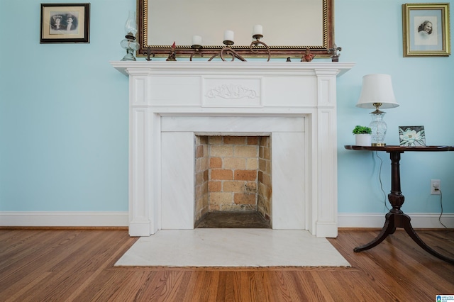 room details with a fireplace with flush hearth, baseboards, and wood finished floors