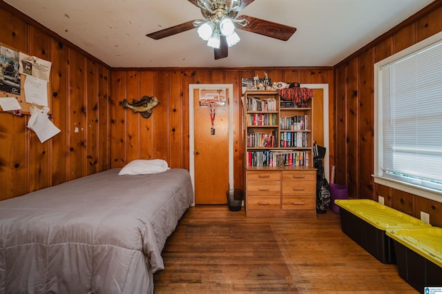 bedroom featuring wooden walls, a ceiling fan, and wood finished floors