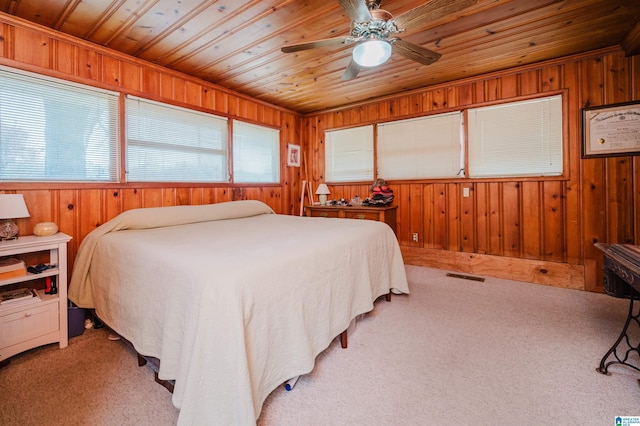 bedroom with wood ceiling, visible vents, wood walls, and light carpet