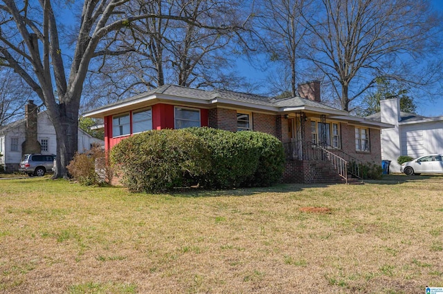 ranch-style house with brick siding, a chimney, and a front yard