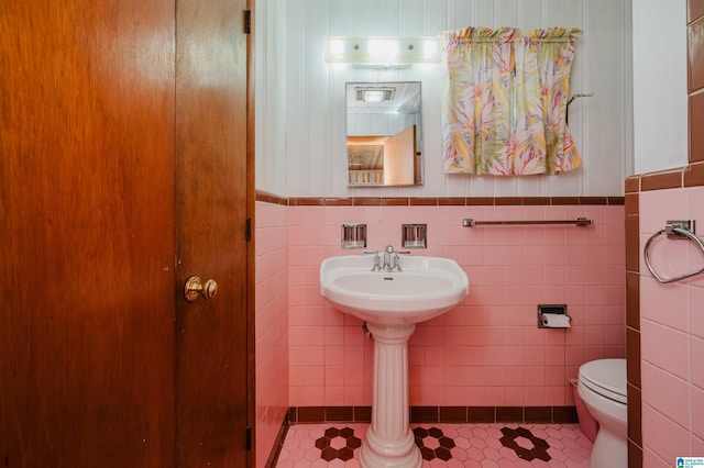 bathroom featuring tile patterned floors, toilet, tile walls, and a wainscoted wall