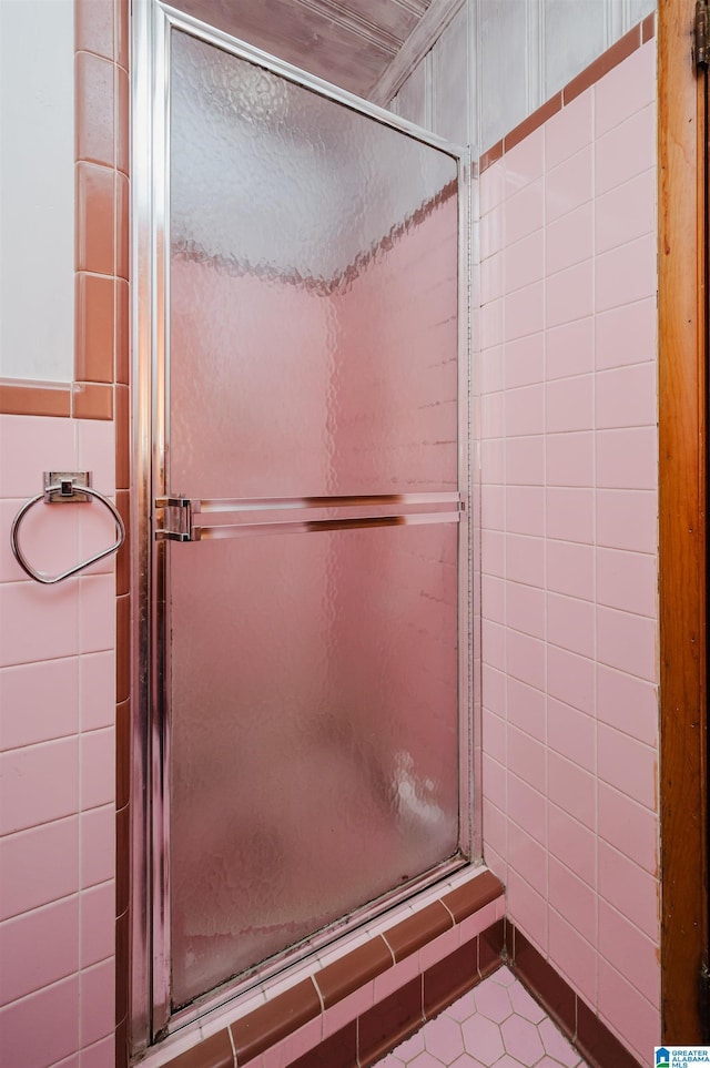 full bathroom with tile patterned floors, a stall shower, and tile walls