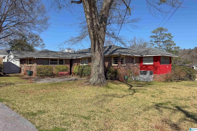 view of front facade featuring a front yard, brick siding, central AC, and a patio