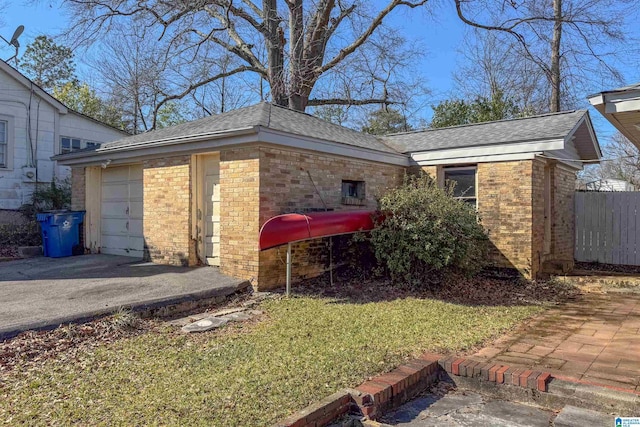 view of side of property with brick siding, a garage, aphalt driveway, and roof with shingles