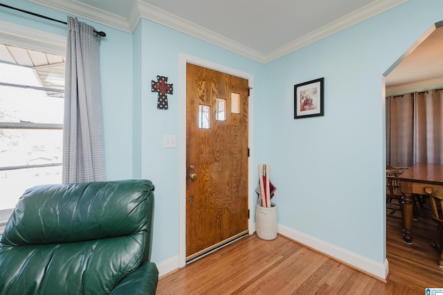 entryway with light wood-type flooring, baseboards, and crown molding