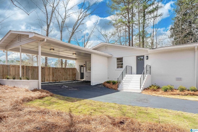 exterior space with crawl space, an attached carport, driveway, and fence