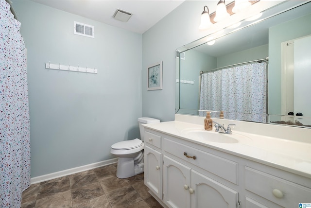 bathroom with toilet, vanity, visible vents, and baseboards