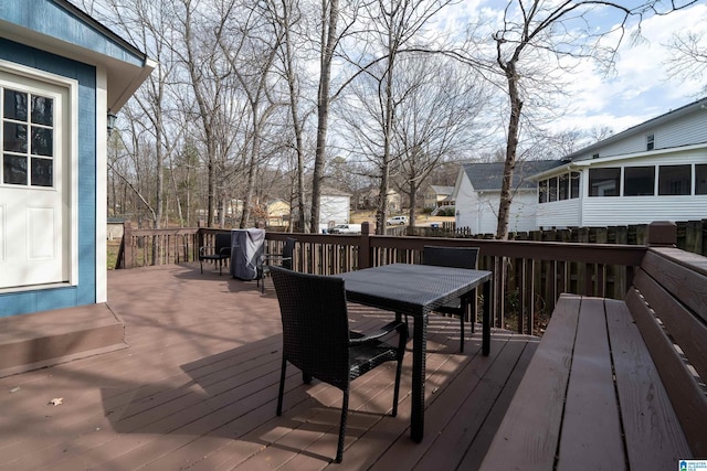 wooden terrace with outdoor dining area and a sunroom