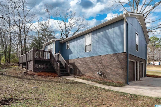 view of property exterior featuring concrete driveway, stairway, an attached garage, a wooden deck, and brick siding