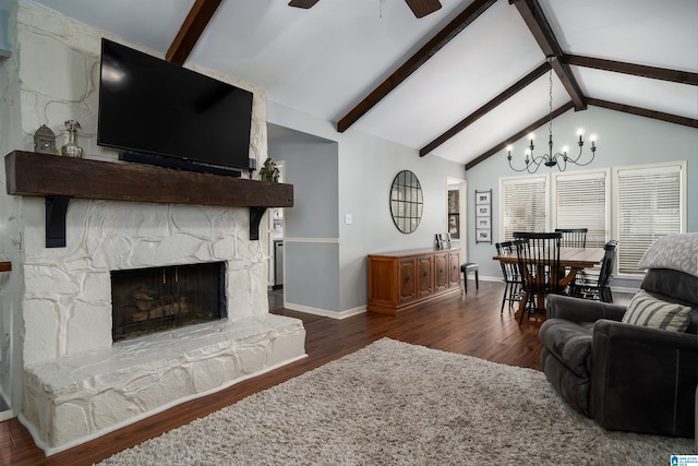 living room featuring vaulted ceiling with beams, ceiling fan with notable chandelier, a fireplace, baseboards, and dark wood-style floors