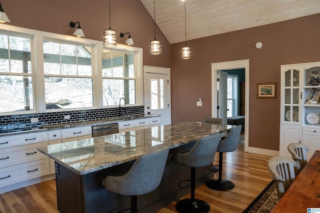 kitchen featuring stainless steel dishwasher, white cabinetry, tasteful backsplash, and light wood finished floors