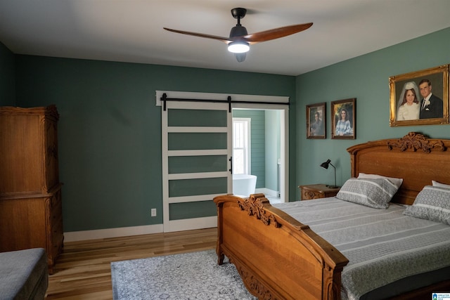 bedroom featuring baseboards, a ceiling fan, a barn door, and wood finished floors