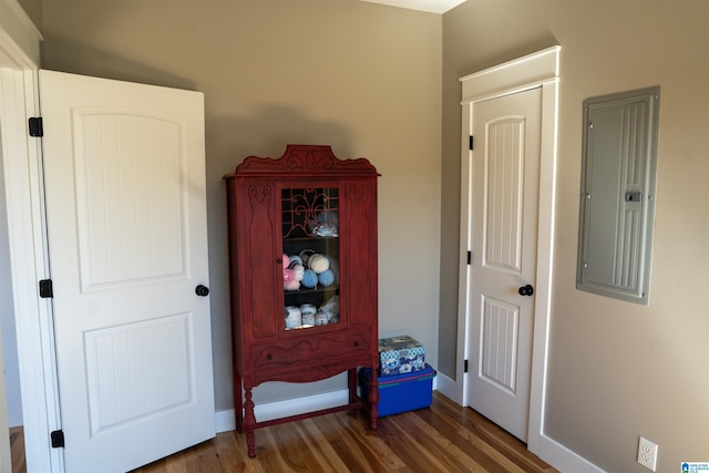 hallway with electric panel, wood finished floors, and baseboards