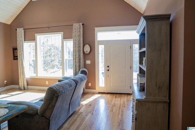 foyer with baseboards, lofted ceiling, and light wood finished floors