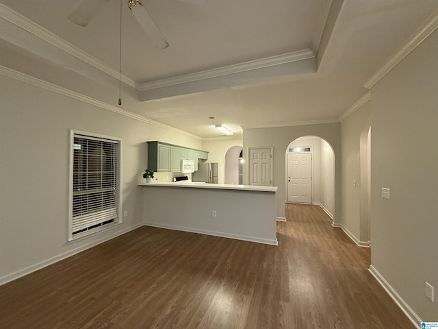 interior space with crown molding, a tray ceiling, arched walkways, and dark wood-style flooring