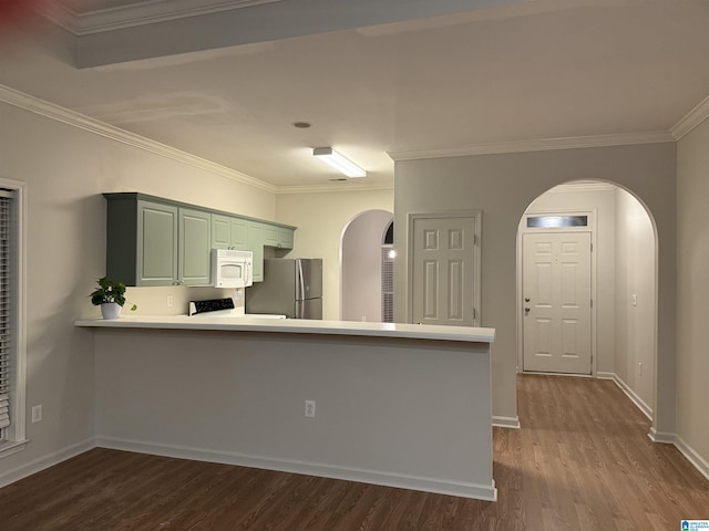 kitchen featuring arched walkways, dark wood finished floors, light countertops, white microwave, and freestanding refrigerator