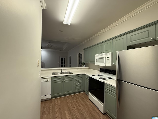 kitchen featuring dark wood-style flooring, light countertops, ornamental molding, a sink, and white appliances