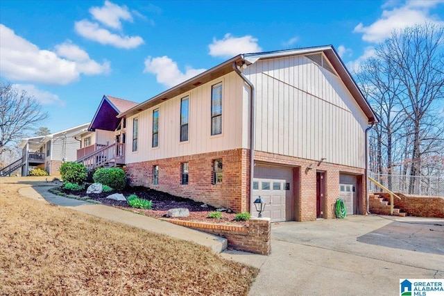 view of side of property with concrete driveway, brick siding, stairway, and an attached garage