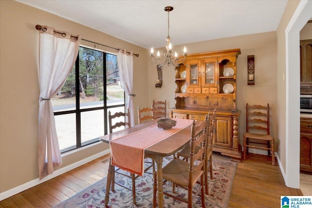 dining space with a chandelier, baseboards, light wood-style flooring, and a healthy amount of sunlight