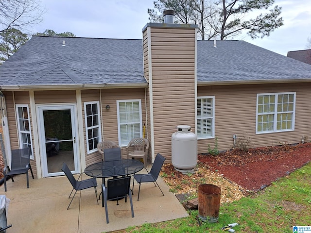 back of house featuring a chimney, roof with shingles, and a patio area