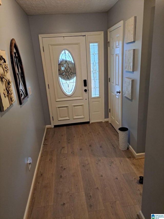 entryway featuring a textured ceiling, baseboards, and wood finished floors