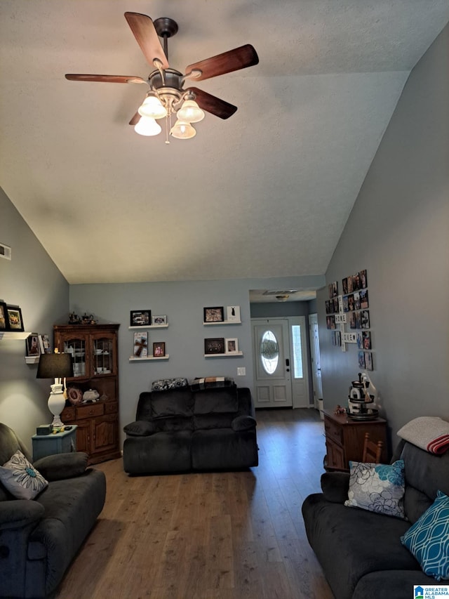 living area featuring ceiling fan, visible vents, vaulted ceiling, and hardwood / wood-style floors