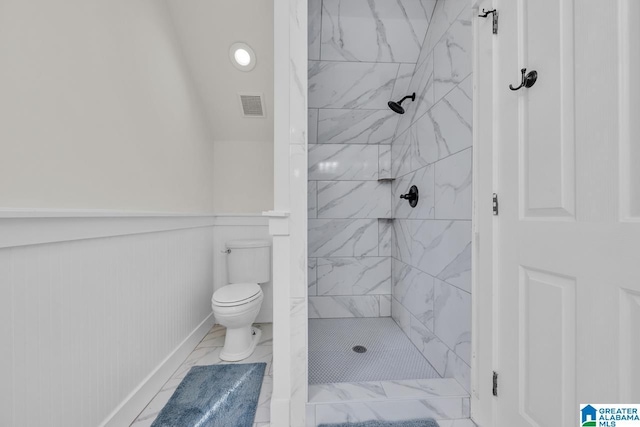 full bath featuring visible vents, toilet, a wainscoted wall, marble finish floor, and a tile shower