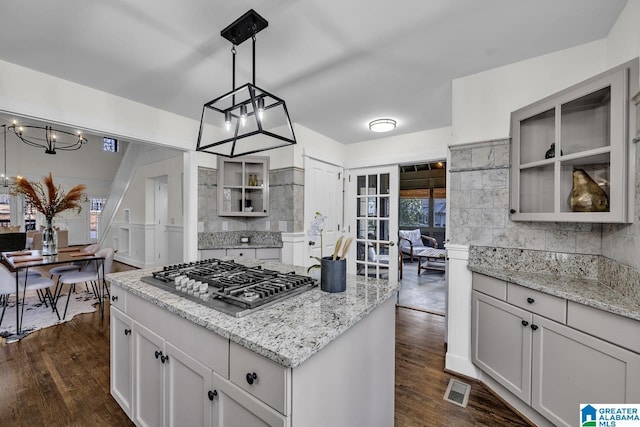 kitchen featuring stainless steel gas cooktop, dark wood-style flooring, backsplash, and glass insert cabinets