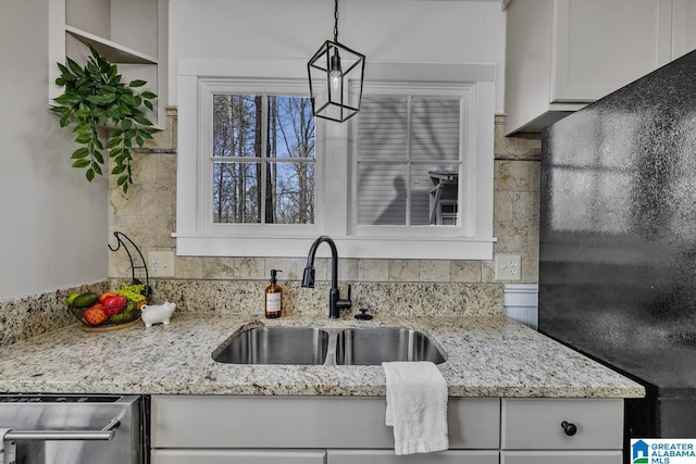 kitchen featuring decorative backsplash, white cabinetry, a sink, light stone countertops, and dishwasher