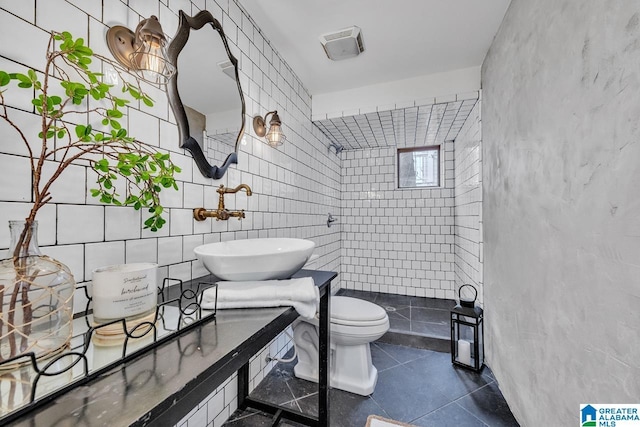 bathroom with toilet, a sink, tile walls, tiled shower, and tile patterned floors