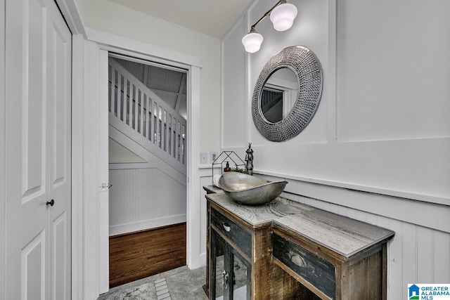 room details featuring wainscoting, a decorative wall, wood finished floors, and vanity