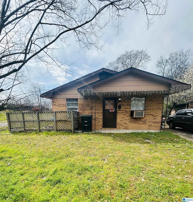 view of front facade with brick siding, a front yard, and fence