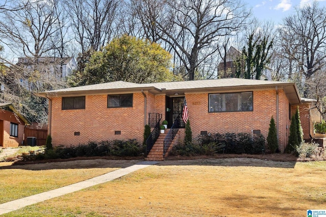 view of front of home featuring a front yard, crawl space, brick siding, and central AC unit