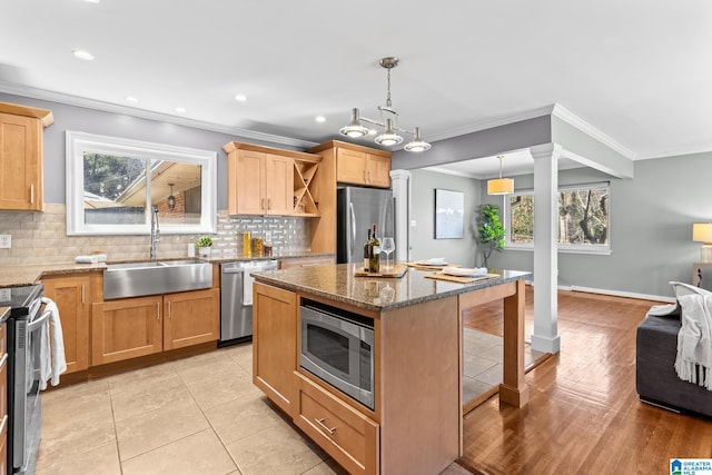 kitchen featuring stainless steel appliances, decorative backsplash, a sink, a kitchen breakfast bar, and ornate columns