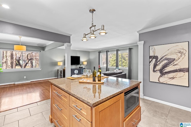 kitchen featuring light stone counters, light tile patterned floors, stainless steel microwave, ornamental molding, and open floor plan