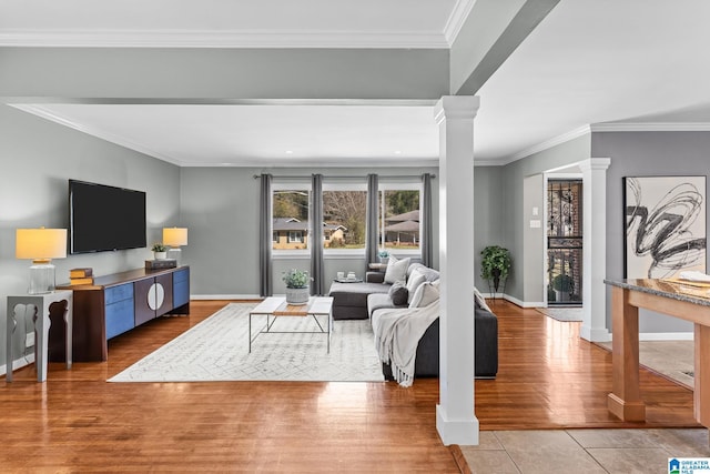 living area with ornamental molding, decorative columns, baseboards, and wood finished floors