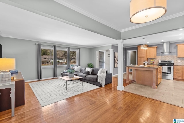 living area with ornate columns, light wood-style flooring, baseboards, and crown molding