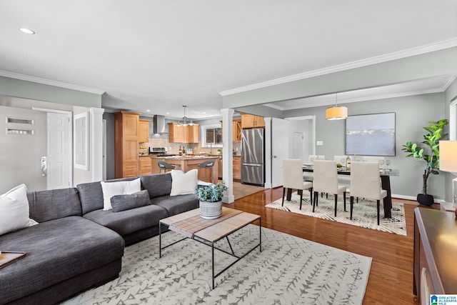 living area featuring recessed lighting, baseboards, ornamental molding, light wood finished floors, and ornate columns