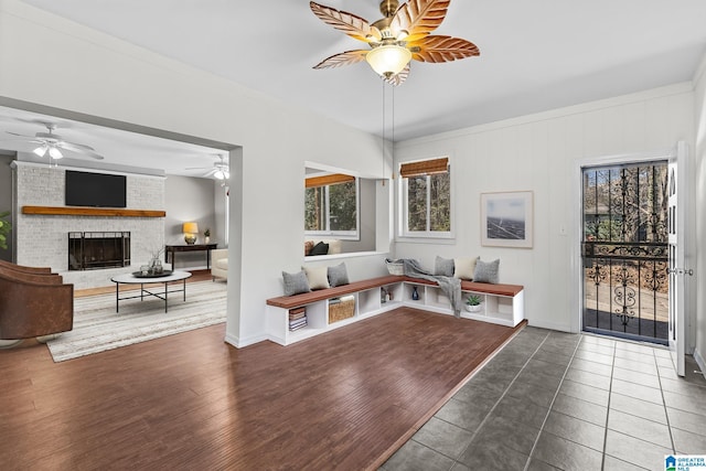 interior space featuring a brick fireplace, a ceiling fan, and wood finished floors