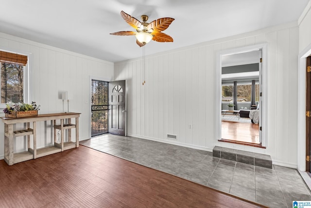 interior space with ceiling fan, wood finished floors, and baseboards