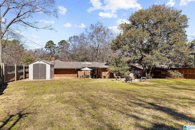 view of yard featuring a shed, a fenced backyard, and an outdoor structure