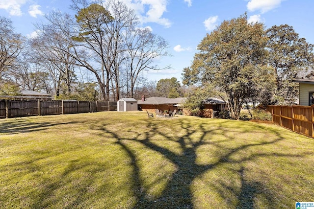 view of yard featuring a shed, a fenced backyard, and an outbuilding