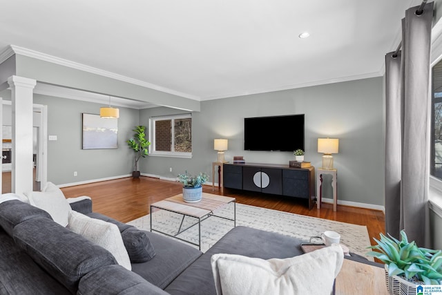 living room featuring baseboards, decorative columns, ornamental molding, and wood finished floors