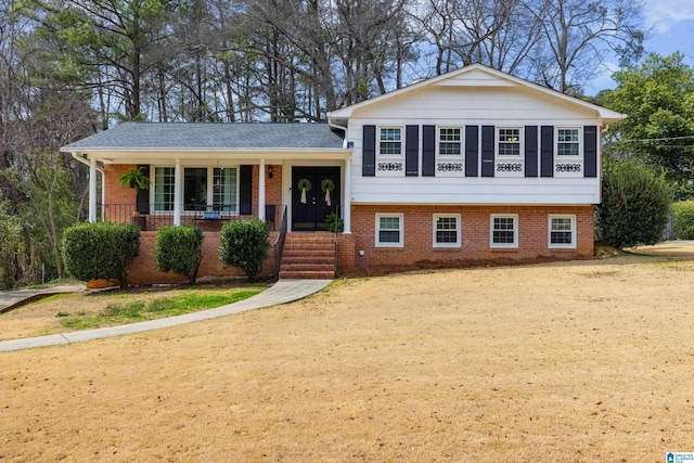 tri-level home featuring driveway, a porch, and brick siding