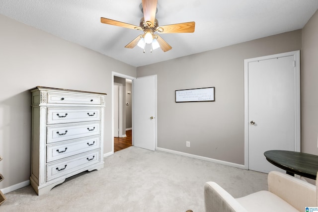 living area with ceiling fan, baseboards, and light colored carpet