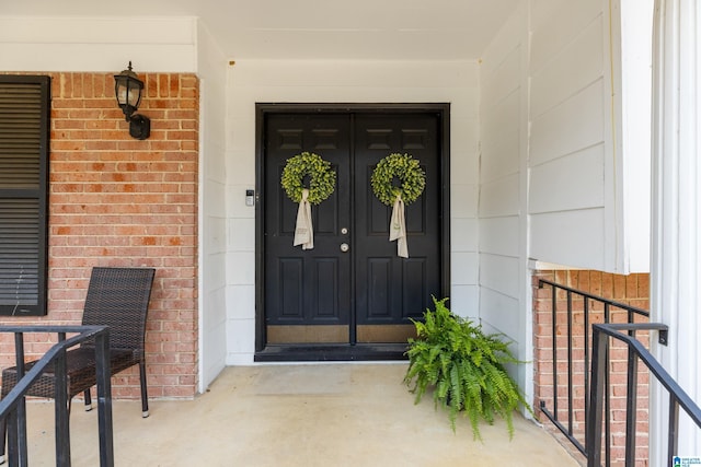 property entrance with a porch and brick siding