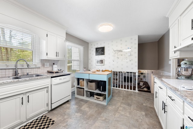 kitchen with white dishwasher, a sink, white cabinetry, and wallpapered walls